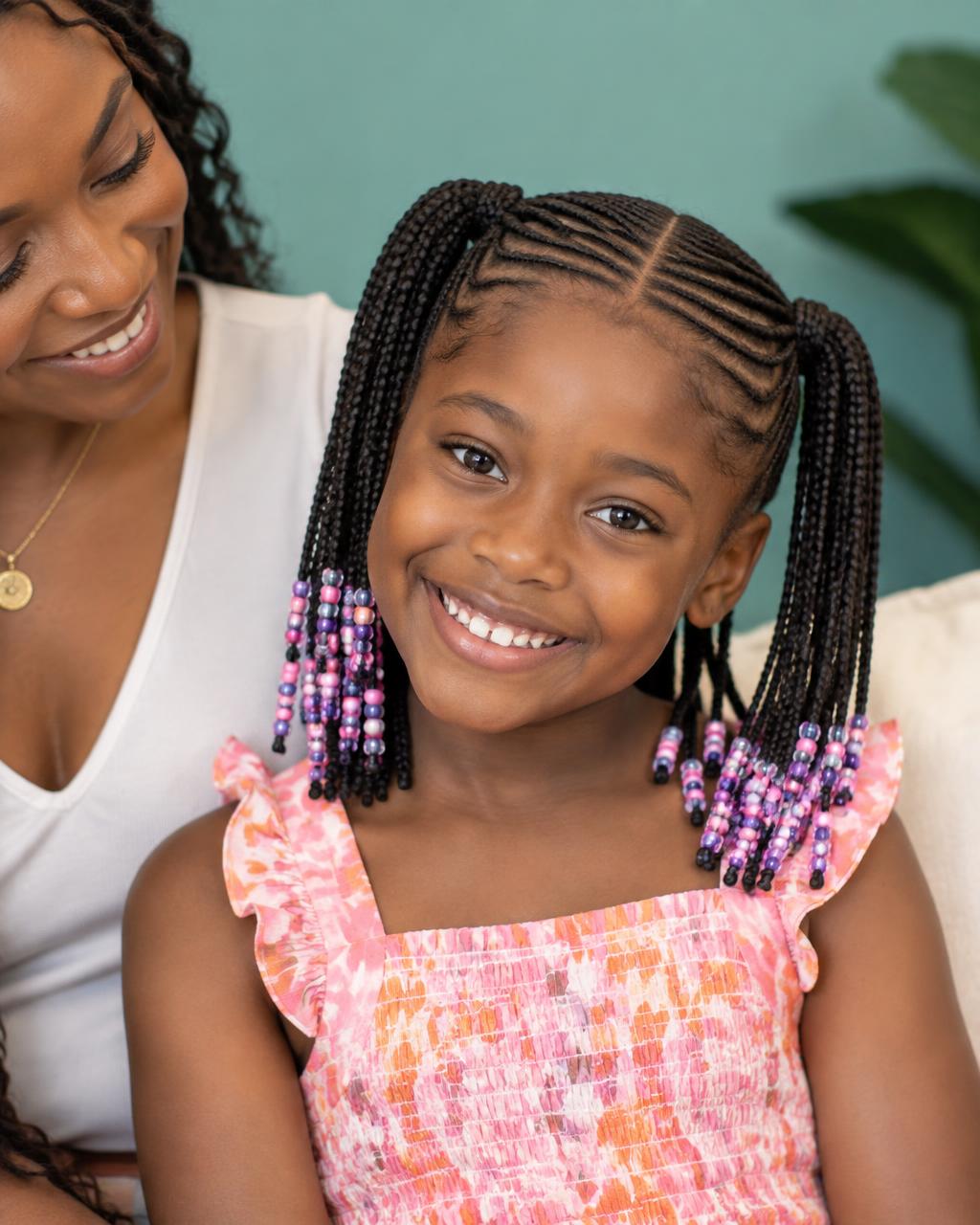 Smiling child wearing braided pigtails with colorful beads